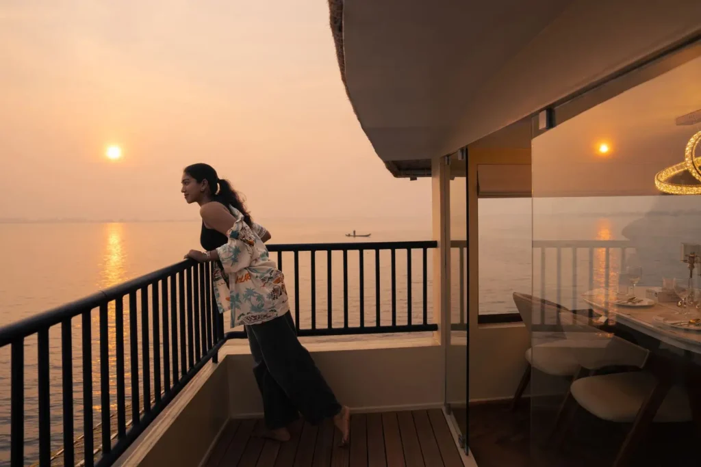 Guest watching the sunset from a houseboat balcony on the Alleppey backwaters